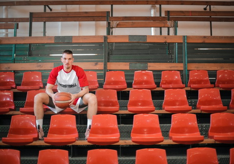 Žaidėjas laiko kamuolį ir sėdi ant raudonų kėdžių
